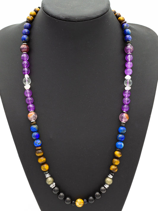 A handcrafted beaded necklace, elegantly displayed on a black bust, featuring a harmonious blend of vibrant gemstones. The beads transition through deep purples, radiant blues, grounding blacks, shimmering golds, and rich earth tones, reflecting cosmic energy balance. Carefully arranged in a symmetrical flow, each bead resonates with spiritual alignment and elemental energy, evoking a sense of grounding, intuition, and empowerment.