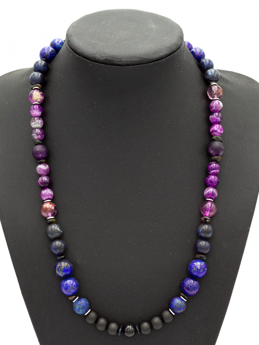 A handcrafted beaded necklace featuring deep indigo and violet stones, designed to enhance the connection to higher consciousness. Rich hues of lapis lazuli, sodalite, amethyst, and charoite blend seamlessly with grounding black onyx and hematite, forming a balanced energetic flow. The beads radiate a celestial glow, activating the third eye and crown chakras for spiritual insight, wisdom, and inner clarity.
